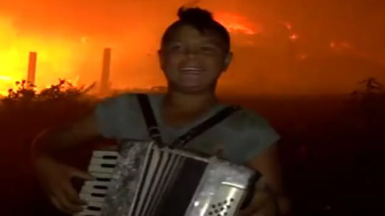 Un copil de etnie romă cântă cu patos la acordeon în faţa unui incendiu de la rampa de gunoi Pata Rât (VIDEO)