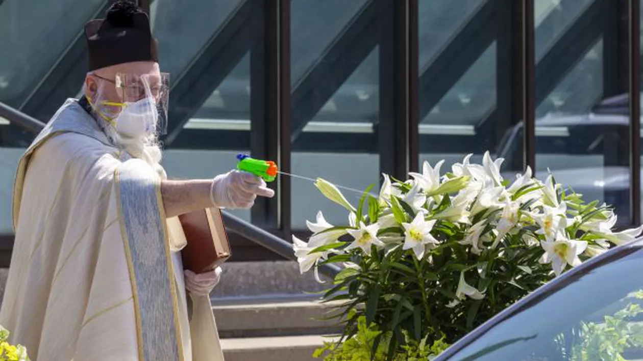 Un preot a stropit cu un pistol umplut cu apă sfințită enoriașii pentru a respecta măsurile de distanțare socială