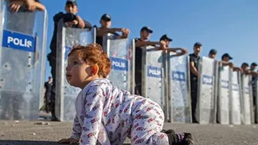 Criza imigranților: Un bebeluș sirian, pozat în timp ce se joacă în fața cordonului de poliţie din Turcia (FOTO)