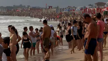 Sute de oameni stau la malul apei în Eforie Nord. Ei se uită la mare extrem de agitată